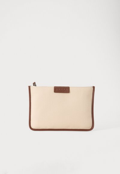 Petite pochette rectangulaire beige en toile avec garniture en cuir marron et une étiquette en cuir marron à l'avant, sur fond blanc.