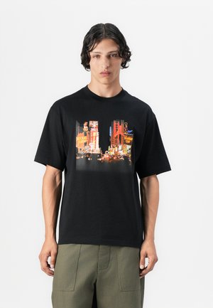 Camiseta de algodón negra con un gráfico central de letreros de neón en colores vibrantes, cuello redondo y corte relajado con mangas cortas.