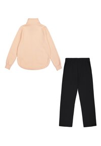 Sudadera de forro polar rosa claro con cuello alto, mangas largas y dobladillo redondeado, junto a pantalones de jersey negros con una cinturilla elástica.