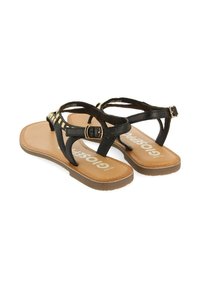Sandalias negras con suelas planas, que presentan un diseño de tiras y un acento dorado. La plantilla es de color marrón claro y la hebilla es ajustable para un mejor ajuste.
