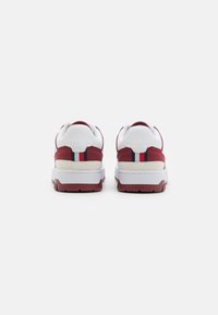 Sneaker bianche e bordeaux con una tomaia testurizzata, colletto imbottito e suola in gomma; presentano strisce sul tallone e un design stratificato.