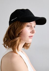 Černá baseballová kšiltovka s zakřiven�ým kšiltem a vyšitým logem "MICHAEL KORS" na boku. Hladký textilní povrch s pevným designem.