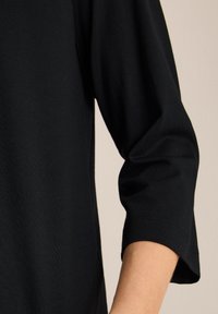 Czarny longsleeve wykonany z miękkiej bawełny, z okrągłym dekoltem i mankietami dla luźniejszego kroju. Prosty i bezszwowy design.