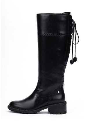 Bota de cuero negro hasta la rodilla con un acabado liso, detalles de cordones en la parte trasera y un tacón ligeramente texturizado para un mejor agarre.
