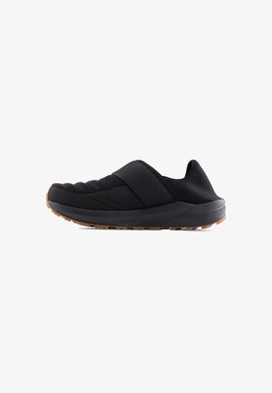 Černé slip-on boty s polstrovaným svrškem, texturovanými síťovými detaily a gumovou podrážkou. Mají design s křížovými popruhy pro bezpečné uchycení.