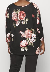 Black floral blouse featuring three-quarter sleeves, designed with large roses and small white flowers, made from a soft, textured fabric.