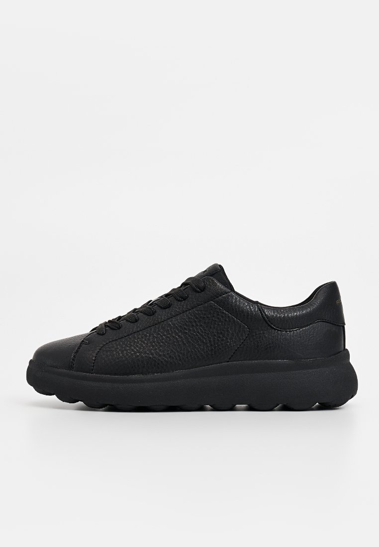 Schwarze Sneaker mit einem strukturierten Lederoberteil, flachen Schnürsenkeln und einer dicken, stabilen Gummisohle. Die Seitenansicht präsentiert ein minimalistisches Design.
