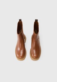 Bottes basses en cuir marron avec une finition lisse, des panneaux latéraux élastiques et des semelles en caoutchouc de couleur claire avec une semelle texturée pour une meilleure adhérence.