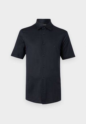 Camicia nera a maniche corte con bottoni, collo classico e piccolo logo sul petto a sinistra, mostrata su uno sfondo chiaro uniforme.
