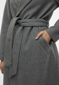 Hallhallane villane kootud mantel isetegemiseks mõeldud mansettidega, küljetasku ja pehme tekstuuriga viimistlus. Lihtne disain, mis pakub sooja ja mugavat tunnet.