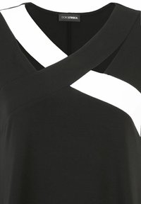Black top with a crossover design featuring white accents. Made of soft fabric, it has a V-neck and short sleeves. Minimalist style.
