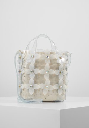 Przezroczysta torebka ozdobiona białymi aplikacjami kwiatowymi z połyskującymi środkami, z beżową materiałową wewnętrzną kieszonką i cienkimi uchwytami.