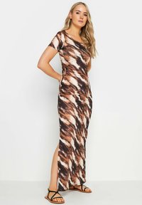 Robe maxi dans un motif tie-dye marron, orange et blanc, à manches courtes et fente sur le côté, fabriquée dans un tissu lisse et extensible.