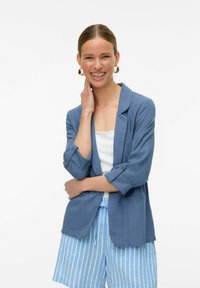 Šviesiai mėlynas blazeris su sukniukėmis, vienu mygtuku užsegimas ir tekstūruota medžiaga, derinamas su mėlynais ir baltais dryžuotais šortais.