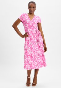Pink floral wrap dress with short sleeves, a v-neck, and a tie waist. The fabric has a soft texture and a full-length skirt.