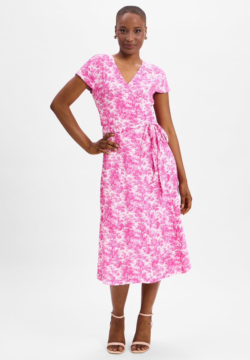 Pink floral wrap dress with short sleeves, a v-neck, and a tie waist. The fabric has a soft texture and a full-length skirt.