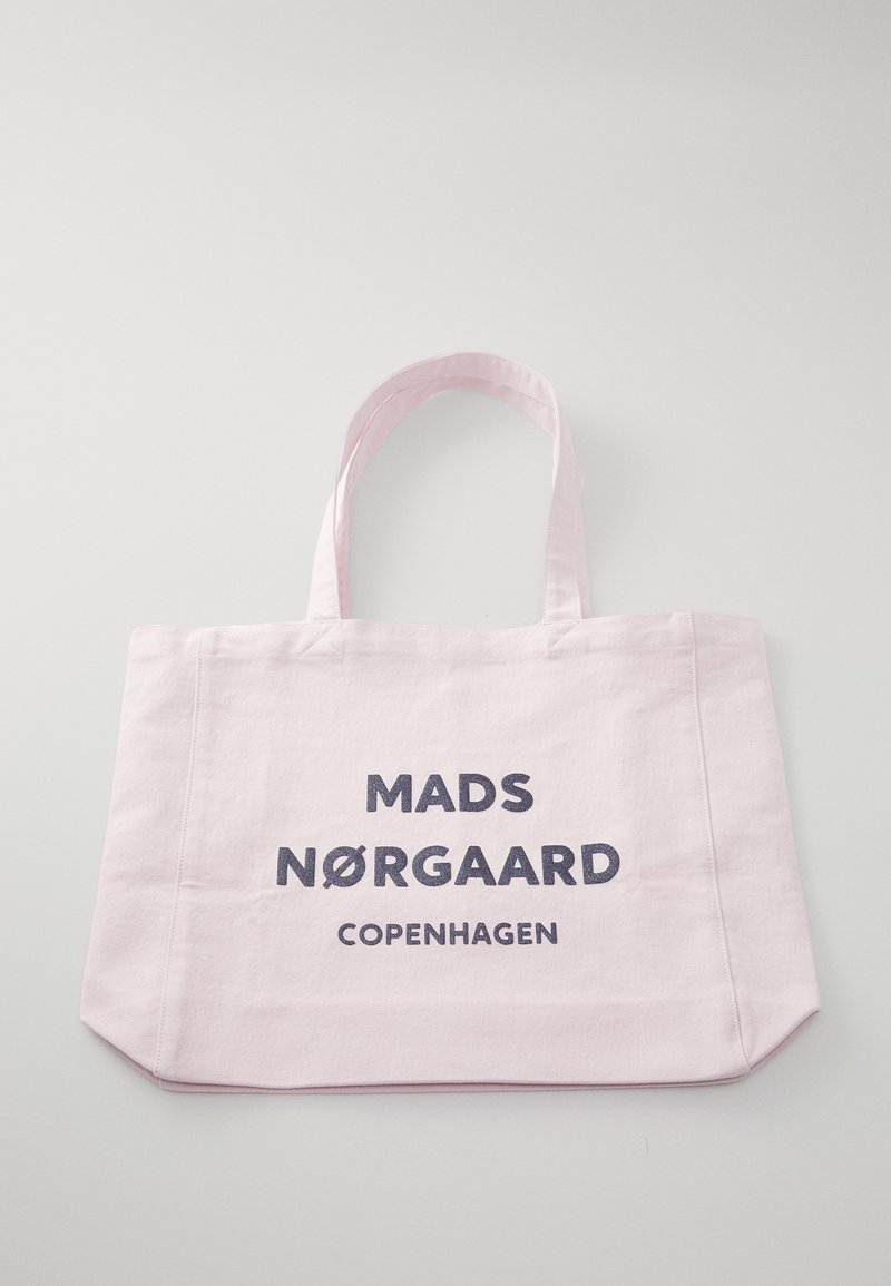 Sac fourre-tout en tissu rose clair avec deux poignées et texte noir "Mads Nørgaard Copenhagen" à l'avant sur un fond uni.