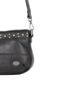 Schwarze Ledertasche mit einem Reißverschluss, Nieten entlang der Oberseite, einem abgerundeten Boden und einem abnehmbaren Tragegurt. Mit einem geprägten Logo auf der Vorderseite.
