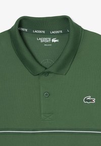 Polo deportivo Lacoste verde con tejido texturizado, cuello acanalado, tapeta de tres botones y pequeño logo bordado en el pecho.