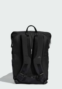 Zaino nero con spallacci imbottiti, dettagli in mesh, maniglia superiore e scomparti con cerniera. Tessuto strutturato e accento marchiato visibile.