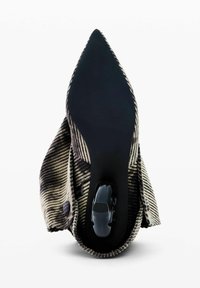 Zapato de punta con una parte superior de tela a rayas en negro y crema. Presenta una suela de goma negra sólida y una rueda integrada para movilidad.