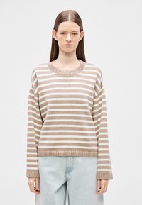 Beežis ja kreemjas triibuline kampsun, soonikkoes ümar kaelus, lahtine lõige, pikad varrukad, pehme kootud tekstuur, kantud helesiniste teksadega.