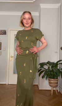Olivengrünes Kleid mit kurzen Ärmeln, Wickeldesign, goldenen Muschelmustern, weichem Stoff, bodenlang und figurbetont.