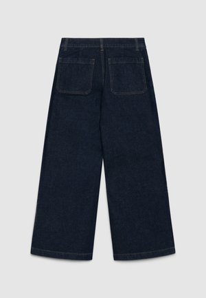 Jeans a gamba larga di colore blu scuro, realizzati in denim, dotati di due tasche posteriori e dettagli cuciti lungo i bordi.