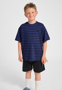 T-shirt met korte mouwen in blauwe en zwarte strepen, van katoen, ronde hals, met een klein logo op de borst, gecombineerd met zwarte korte broek en blauwe schoenen.