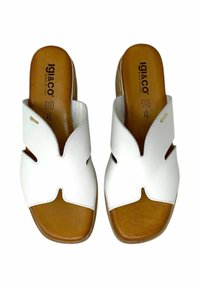 Sandali aperti bianchi in pelle con design a taglio, fondo beige e dettaglio del logo dorato discreto sulla fascia. Made in Italy.