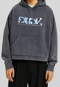 Felpa corta grigio scuro con tasca a marsupio frontale, con stampa grafica di testo blu e bianco che dice "DUSK WHEN THE SUN GOES DOWN."