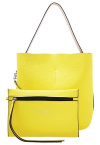 Sac cabas en cuir jaune avec une pochette assortie à fermeture éclair, les deux ornés de bordures noires et une fine bandoulière sur le cabas.