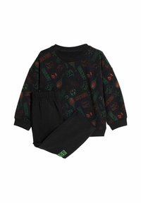 Čierny set mikiny a nohavíc s farebnými motívmi Disney, vrátane športového vybavenia a postavičiek; mäkká tkanina s elastickým pásom.