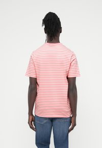 Κοντομάνικο t-shirt σε ανοιχτό ροζ με λεπτές λευκές οριζόντιες ρίγες. Διαθέτει στρογγυλή λαιμόκοψη και χαλαρή εφαρμογή. Κατασκευασμένο από βαμβάκι.