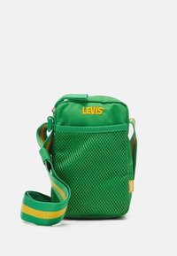 Zielona nylonowa torba przypinana na crossbody z siateczkowym przednim panelem, regulowanym paskiem z zielonymi i żółtymi paskami oraz żółtym logo "LEVİS".