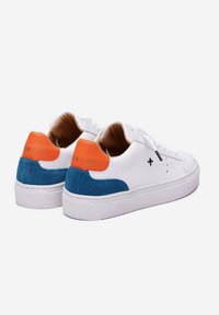 Zapatillas blancas con un panel lateral de ante azul y una lengüeta trasera naranja. Las características incluyen una suela texturizada y acentos de costura negra.