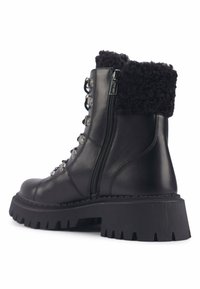 Botín negro de cuero con cuello de piel sintética, que cuenta con una suela gruesa y con relieve, cremallera lateral y ojetes metálicos para los cordones.