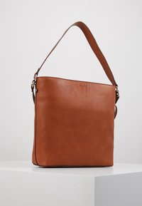 Bolso de hombro de cuero marrón con un acabado texturizado, una correa ancha única y forma plana y rectangular. Presenta una sutil marca en la parte delantera.