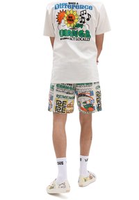 T-shirt blanc avec un graphique coloré et un design de soleil au dos ; shorts à motifs avec des textes vibrants et des illustrations ; chaussures assorties.