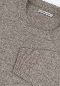 Beige Strickpullover mit rundem Ausschnitt, gerippten Bündchen und einer Brusttasche. Das Material wirkt weich mit einer strukturierten Oberfläche. Das Etikett lautet "DAN JOHN."