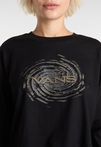 Zwarte langekem shirt met een draaiend grafisch ontwerp in grijs, met daarin het woord "VANS" prominent in het midden weergegeven.