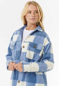 Blauw-witte geblokte fleecejas met een kraag, voorzakken en knoopsluitingen. Zachte textuur en een ontspannen pasvorm.