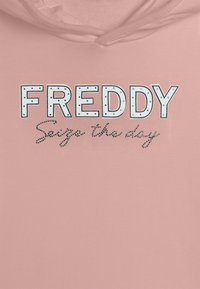 Felpa leggera rosa chiaro con la scritta "FREDDY" in grassetto, lettere maiuscole bianche con possibilità di borchie, e la frase in corsivo "Cogli l'attimo" sottostante.