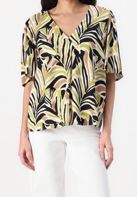 Top corto a maniche corte dal taglio morbido, con un motivo multicolore di foglie nei toni del verde, beige e nero. Presenta un design a scollo a V.