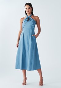 Sinine kaelarätiga õlakaartega kleit, valmistatud kergest materjalist, omades A-lõiget, kahte küljetaskut ja sõlmega esiotsa detaili.