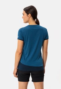 Chemise bleu chiné à manches courtes avec un col arrondi, présentant un ourlet contrastant et un logo subtil sur l'épaule.