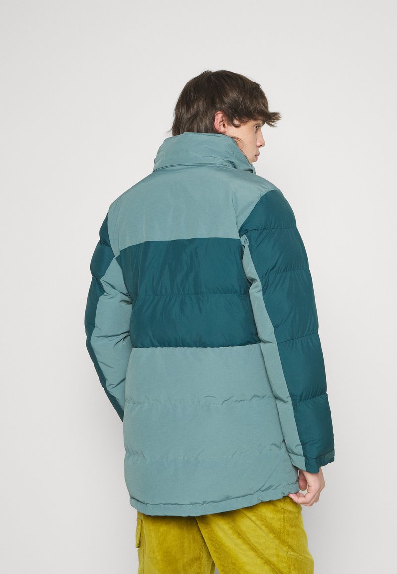 Veste rembourrée avec un design tricolore : bleu sarcelle, bleu clair et bleu marine. Dotée d'un col montant et fabriquée en tissu texturé.