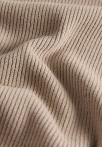 Țesătură bej cu textură nervurată, cu dungi verticale și variații subtile în densitatea firelor, creând un aspect confortabil.