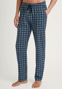 Blauwe en zwarte geruite pyjamabroek met een elastische tailleband en koord. Bevat zijzakken en heeft een ontspannen pasvorm. Gemaakt van katoen.