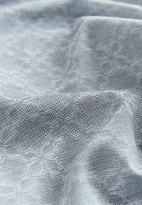Tissu texturé bleu clair avec un motif géométrique subtil et des détails fins. Matériau doux et tissé avec une finition lisse.